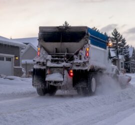 Truck with snow plow clearing parking lot snow