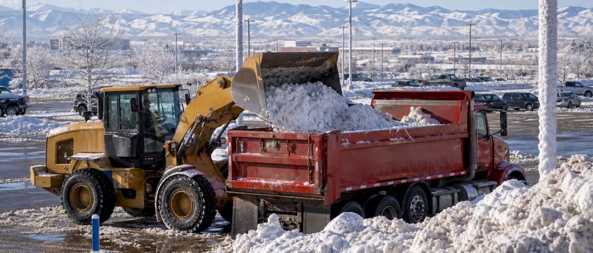 Front-end loader loading snow into a dump truck outdoors