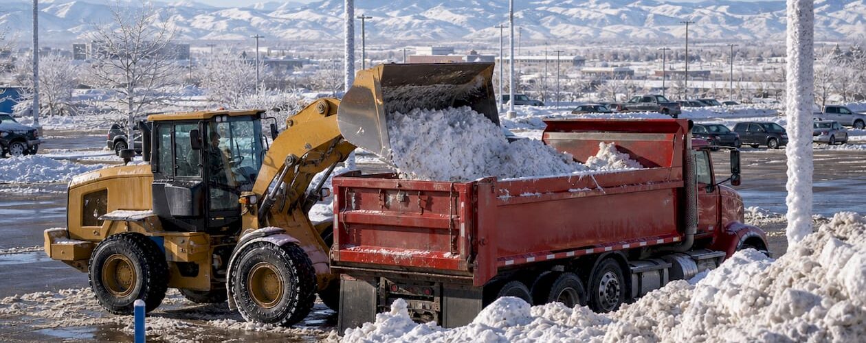 Front-end loader loading snow into a dump truck outdoors