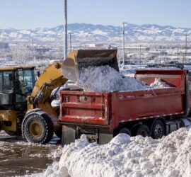 Front-end loader loading snow into a dump truck outdoors