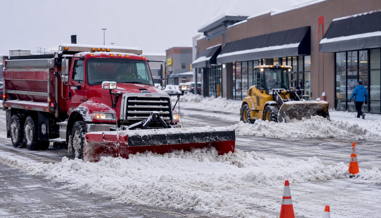Snow removal crew clearing retail parking lot