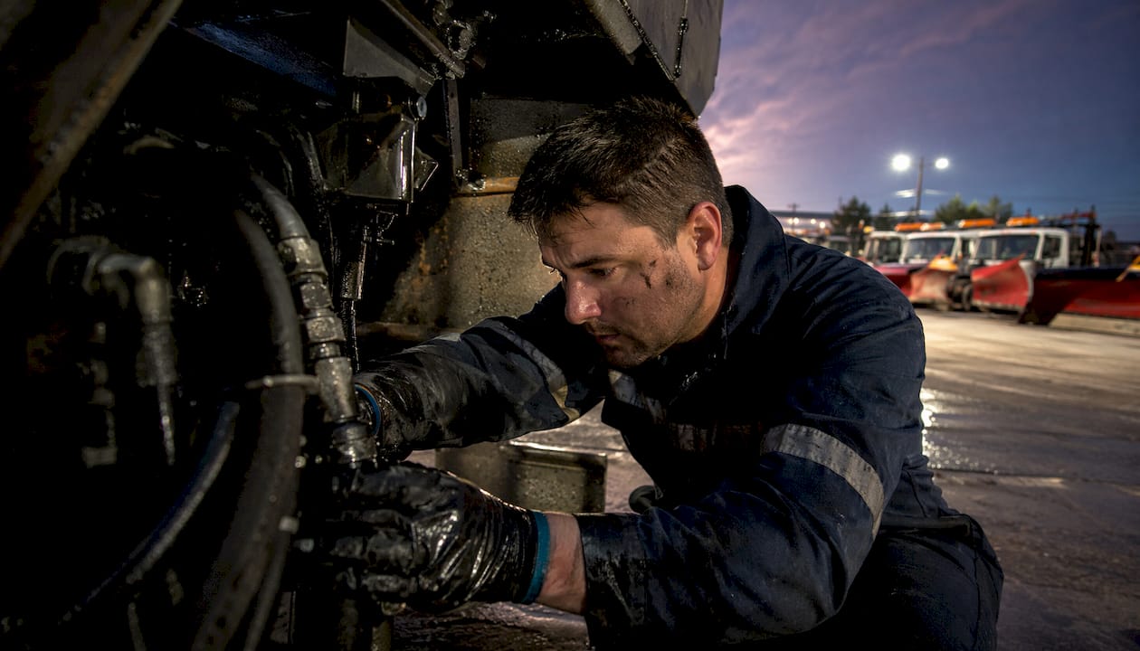 Mechanic servicing commercial plow truck indoors