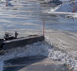 Snow plow clearing commercial parking lot snow