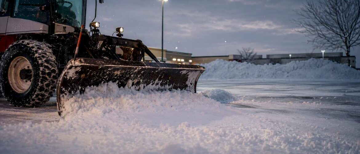 Snow plow clearing commercial parking lot in Denver