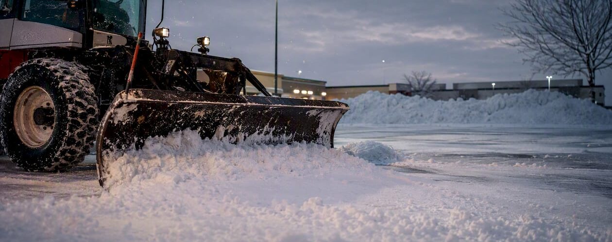 Snow plow clearing commercial parking lot in Denver