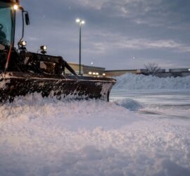 Snow plow clearing commercial parking lot in Denver