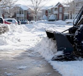 Snow removal equipment clearing sidewalk in HOA neighborhood