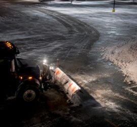 Snow plow clearing driveway at night