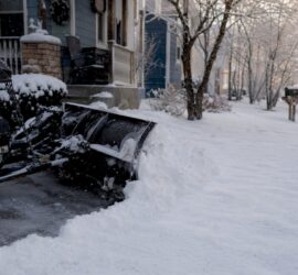 Snow plow clearing fresh snow at property entrance