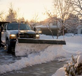 Snow plow clearing residential driveway morning light